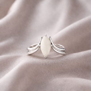 Silver wishbone ring featuring a pure breastmilk stone, photographed on soft champagne silk fabric.